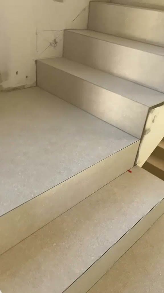 Marches et contremarches habillées de grès cérame beige aspect pierre à Thonon-les-Bains, arêtes nettes sans profilé et petites cales encore visibles