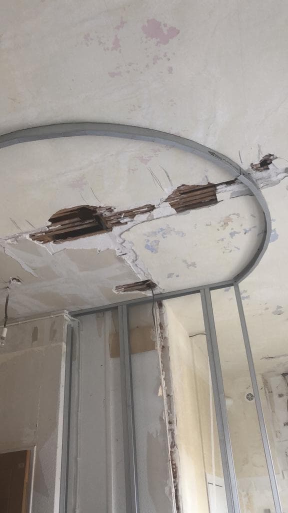 Curage d’un appartement ancien à Aix-les-Bains : plafond en plâtre dégradé laissant voir le lattis bois, rail métallique cintré et montants pour une cloison arrondie